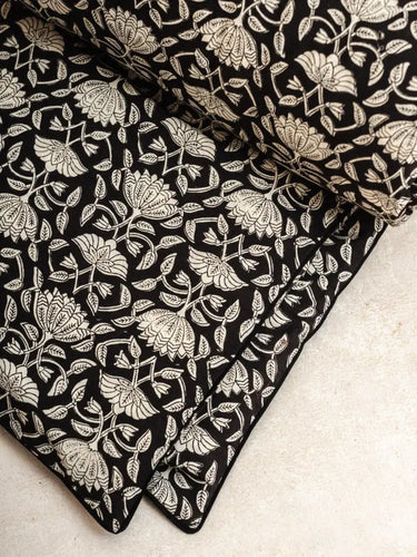 Housse de SofaCover  en coton imprimée à la main, motifs graphiques Lotus Noir. Finition passepoil élégante, déhoussable et lavable, idéale pour un intérieur éco-responsable et modulable.